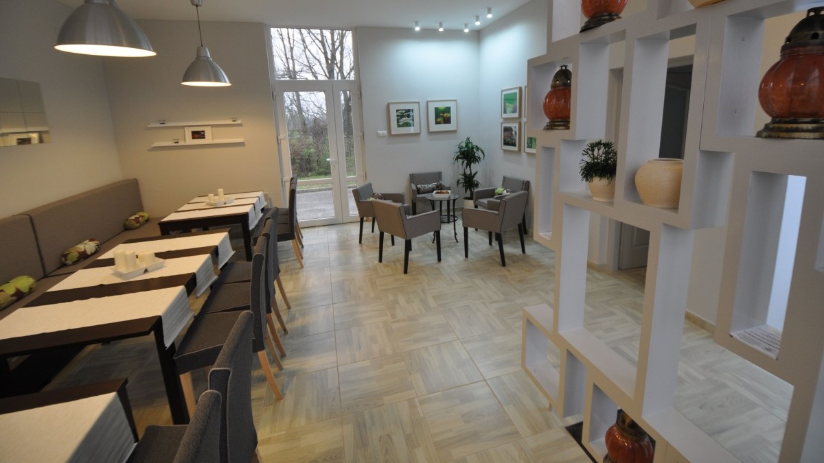 Rendezvényterem belső tér, világos színű falak, melyen képek és televízió van.