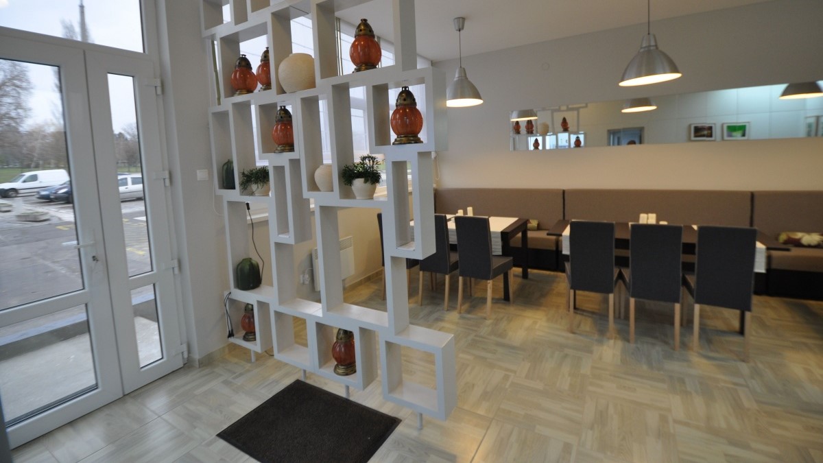 Belső tér, világos színű falak, zöld növények, televízió a falon.