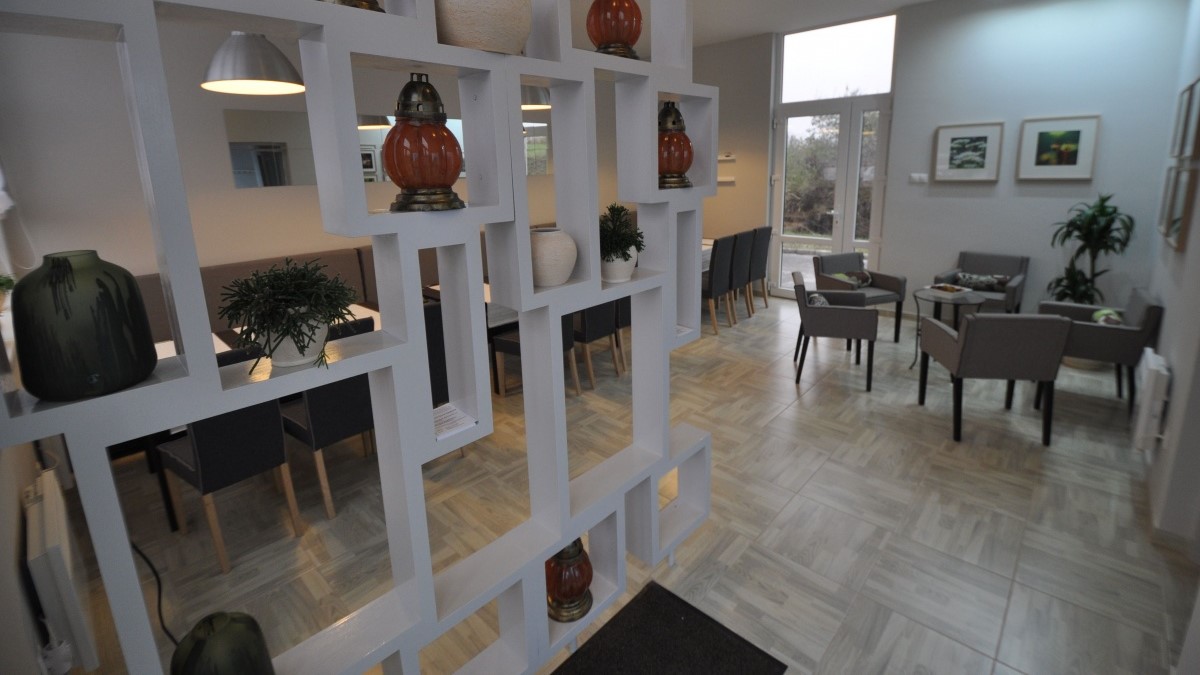 Rendezvényterem, sötét színű asztalok megterítve.