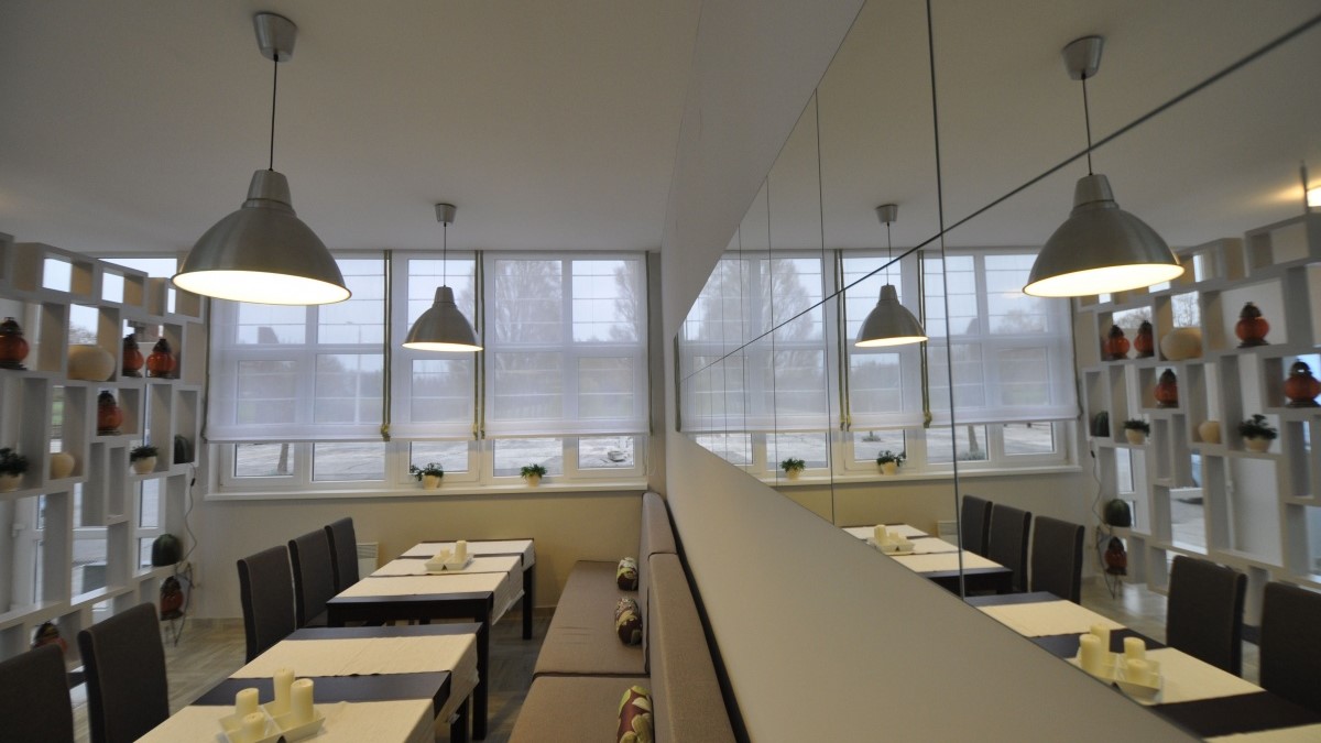 Belső enteriőr, világos színű falak, sötét színű asztalok.